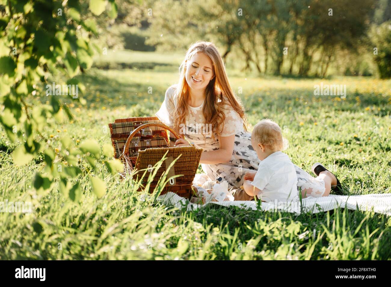 Happy parents mom with daughter on a picnic are walking in the park in summer. Stock Photo