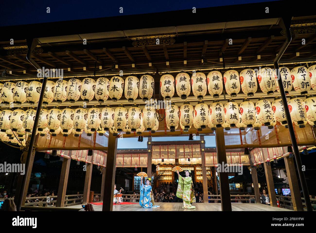 Geisha wearing kimono dancing and performing on stage in front of audience. Beautiful and elegant maiko. Yasaka Shrine, Kyoto, Japan. Stock Photo