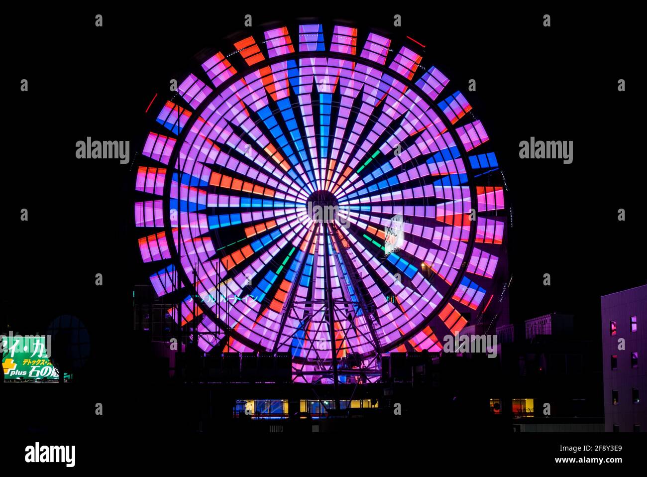 Sapporo Ferris Wheel, colourful neon lights illuminated at night. Funfair wheel on top or a skyscraper. Hokkaido, Japan. Stock Photo
