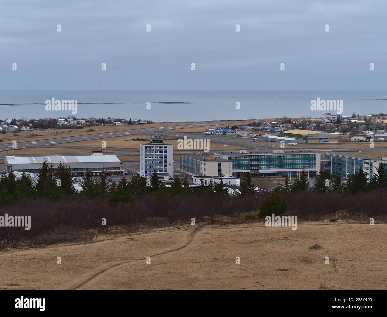 Aerial view of Reykjavik domestic airtport with runway and terminal building viewed from Perlan on Öskjuhlíð hill on cloudy winter day. Stock Photo