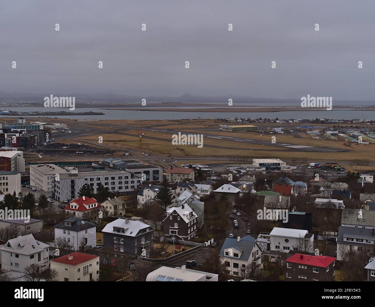 Aerial panoramic view over the southern part of Reykjavik downtown with runway of domestic airport (Reykjavíkurflugvöllur), buildings and mountains. Stock Photo