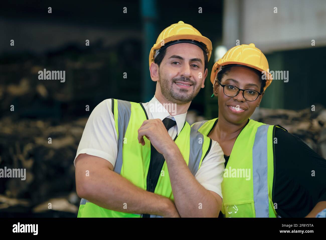 Couple friend Team Worker mix race  enjoy working in heavy factory standing together happy smiling portrait shot looking camera Stock Photo