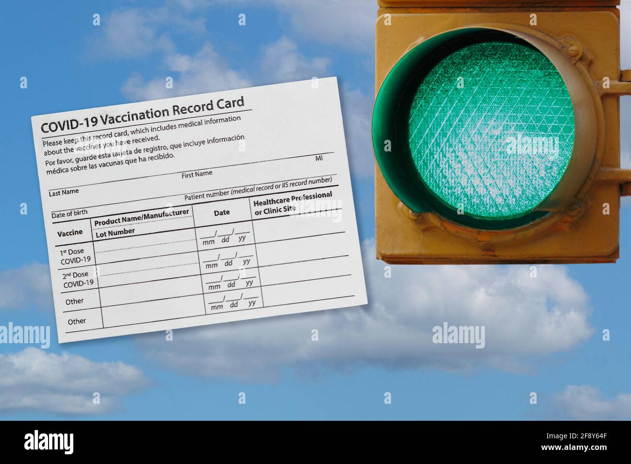 photo collage of covid-19 vaccination record card and a green traffic light against a sky, representing opening as more people are vaccinated Stock Photo