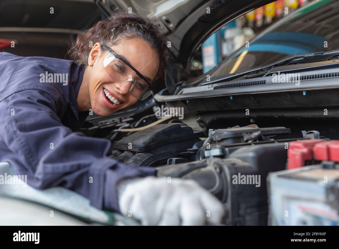 Woman worker at automobile service center, Female in auto mechanic work in garage car technician service check and repair customer car, inspecting car Stock Photo