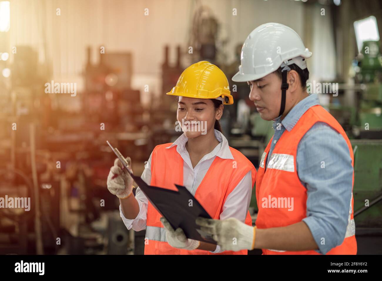 Two engineer worker man and women working together , Asian young people work as teamwork help support together happy smile in factory heavy industry Stock Photo