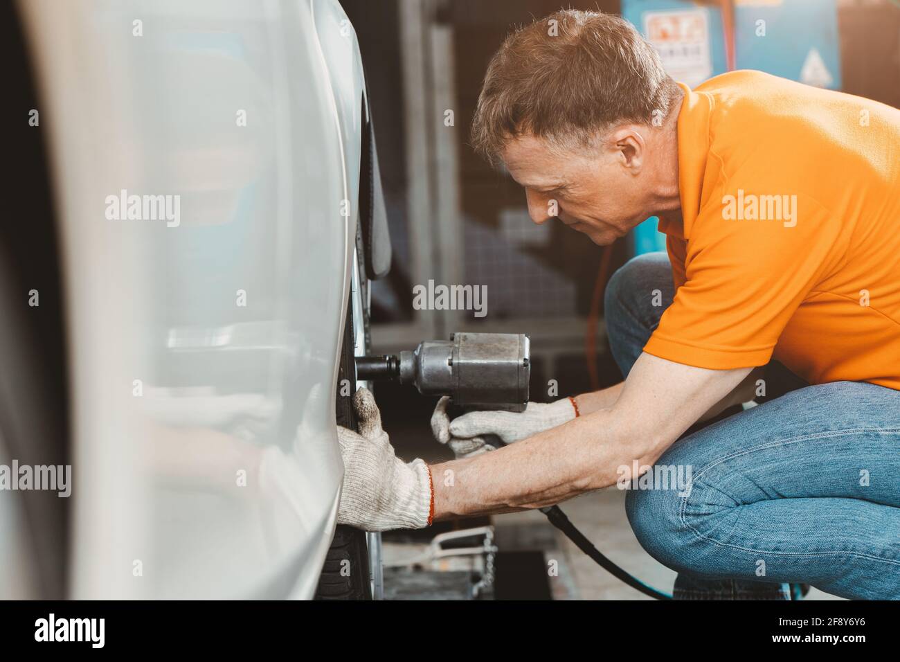 professional car tire service man worker at automobile service center, male in auto mechanic work in garage car technician service check and repair cu Stock Photo