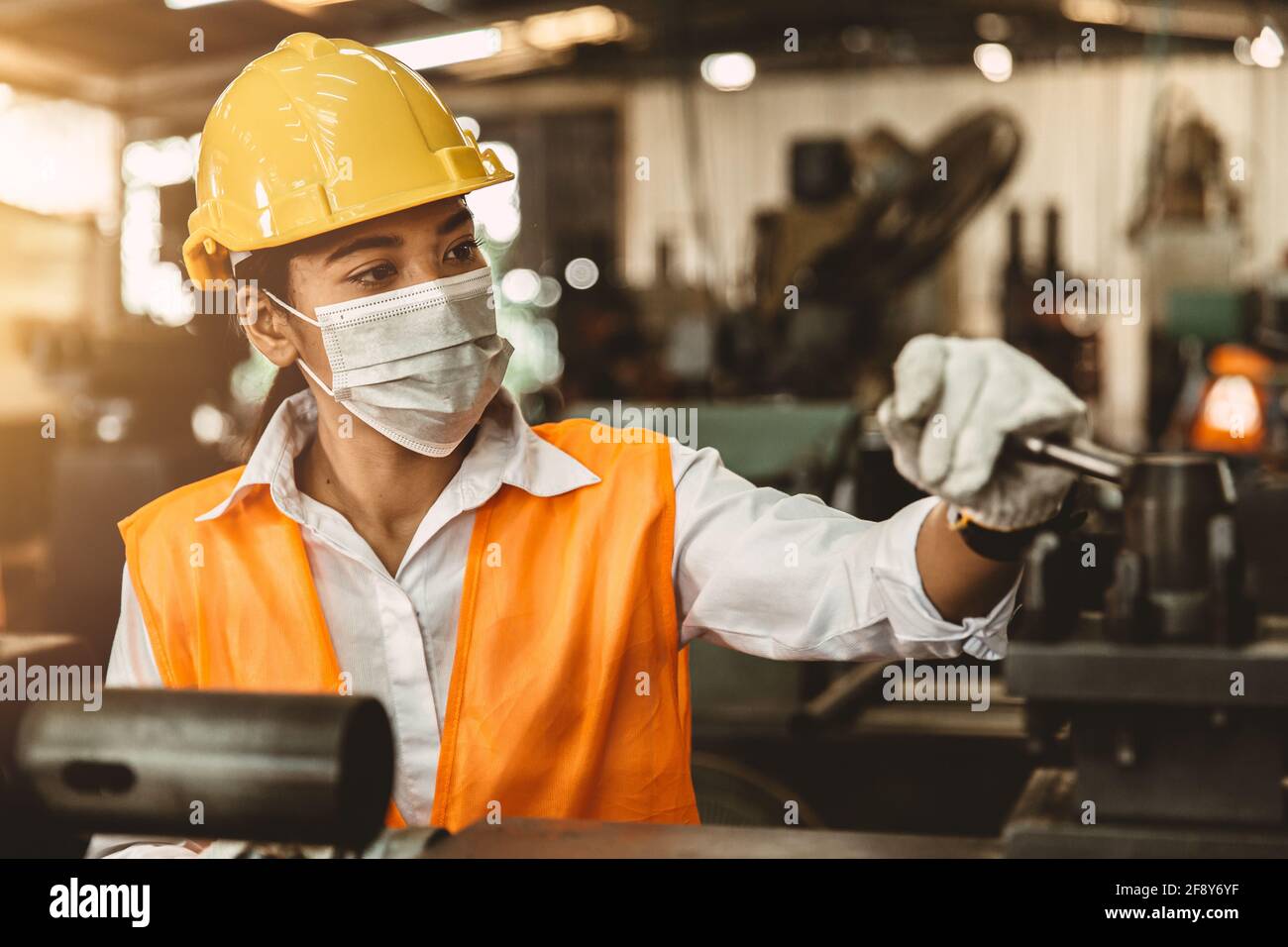 Asian Woman Worker with Safety Helmet and Face Mask Working as Labor in Heavy Industry Factory. Stock Photo