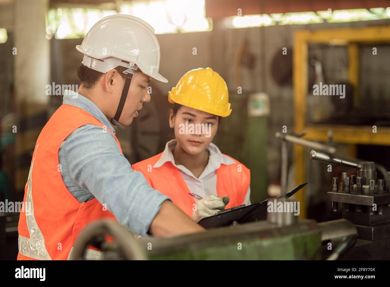 Engineer team male with working women work together in heavy industry teach and train machine operation in factory Stock Photo