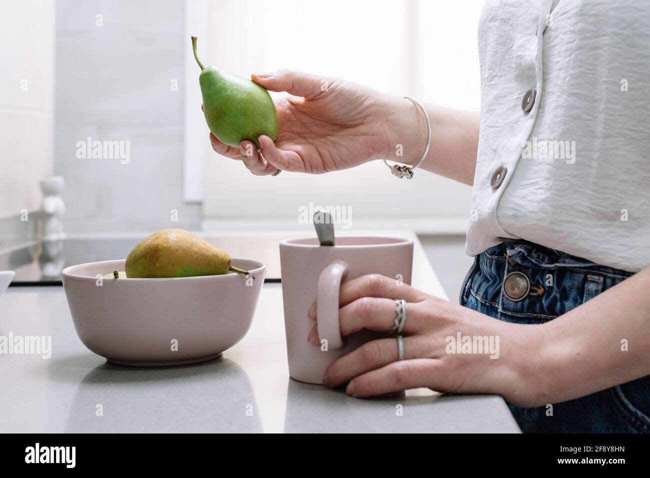 Woman holding fresh ripe pear in kitchen Stock Photo