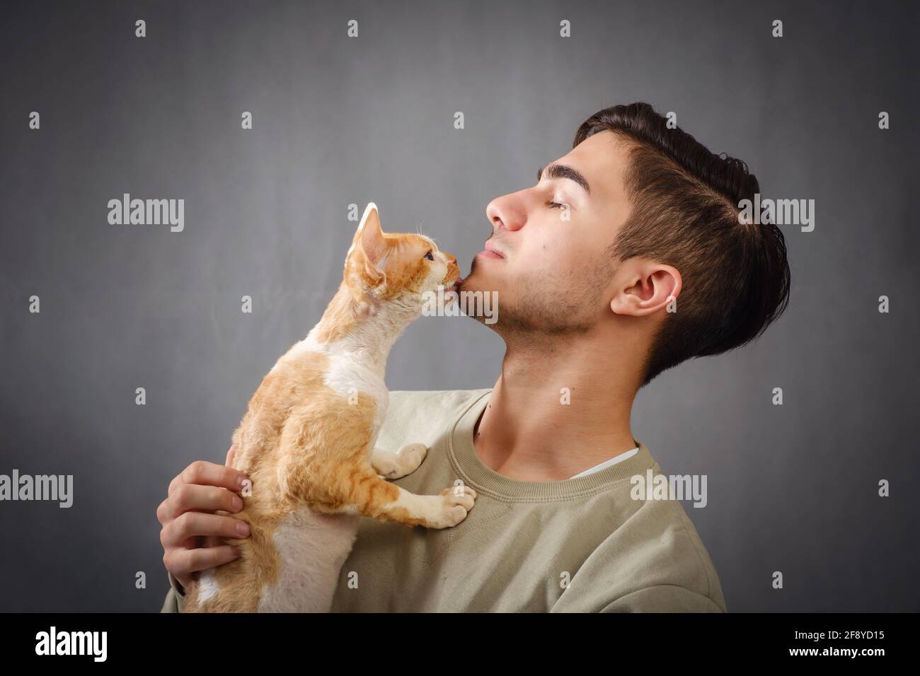 Man holding and kissing muzzle cute Devon rex cat Stock Photo