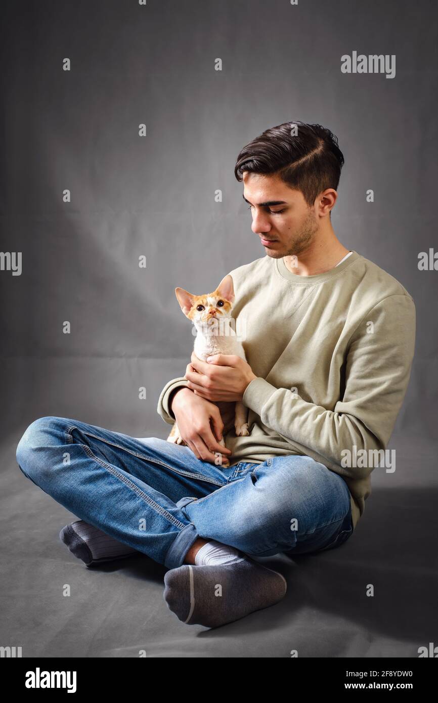 Man holding and kissing muzzle cute Devon rex cat Stock Photo