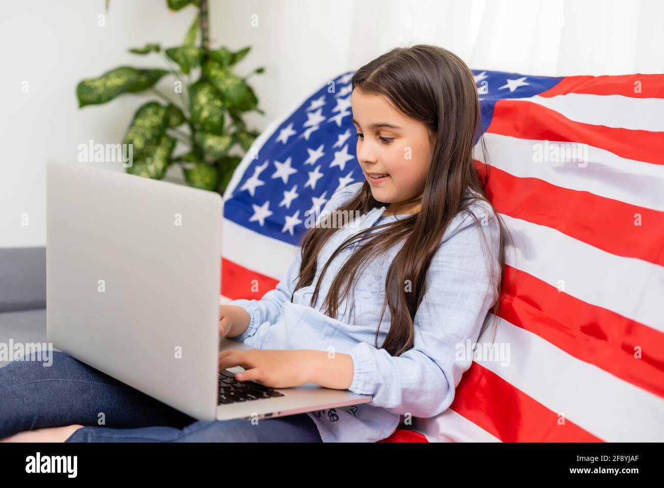 Back to online school education. Difficult to speak English. Kid doing homework on computer. Student studying on laptop over American flag. Tutor Stock Photo
