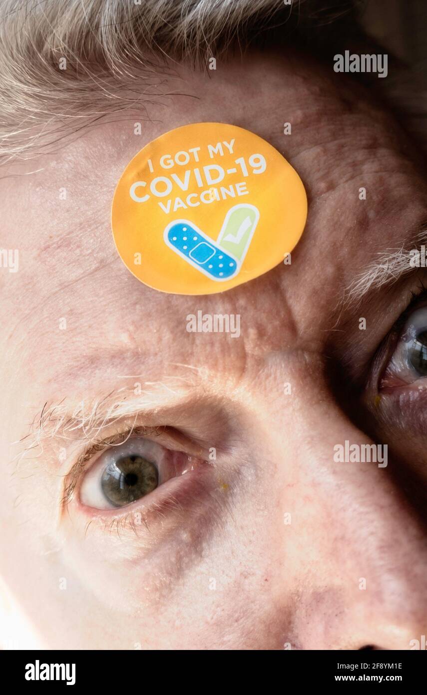 Senior man with an 'I got my COVID-19 vaccine' sticker on his forehead, United States Stock Photo