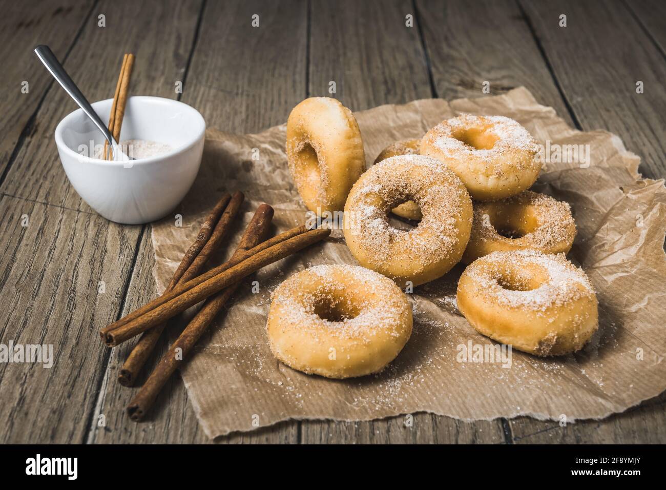 Mini donuts with sugar and cinnamon on a paper on a wooden table Stock Photo