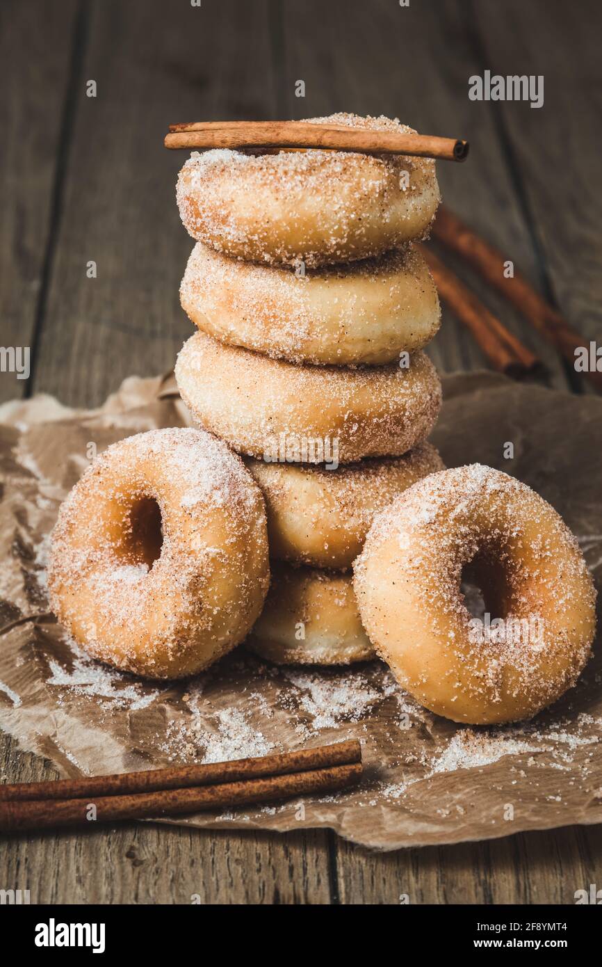 Sugared stacked mini donuts with cinnamon on a wooden table, vertical Stock Photo