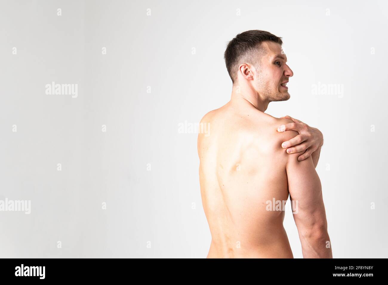 A sore shoulder joint muscle in a white man on a white background back ...