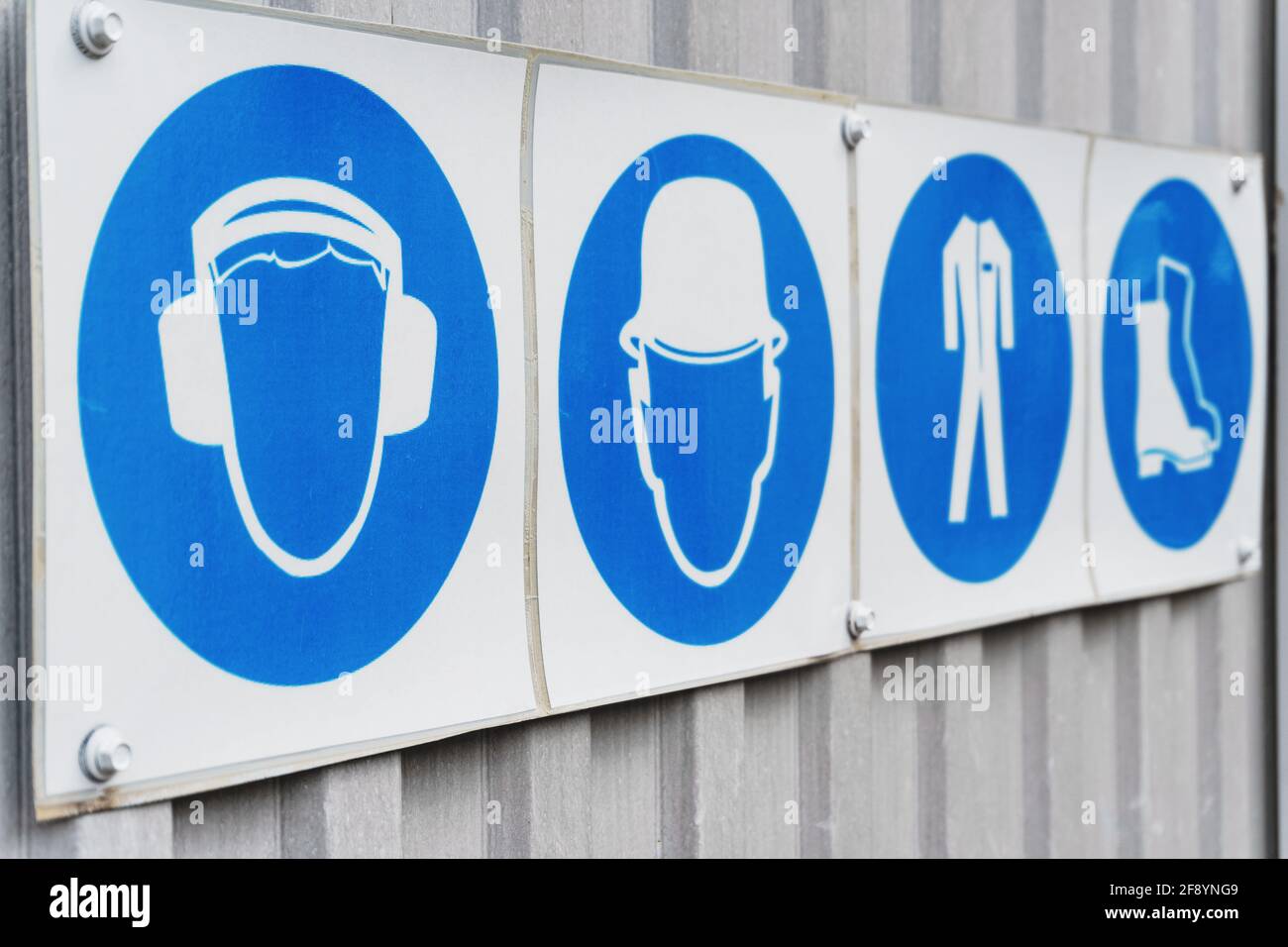 Safety signs and posters of personal protective equipment at work. Headphones, helmet, workwear, safety shoes in a row Stock Photo