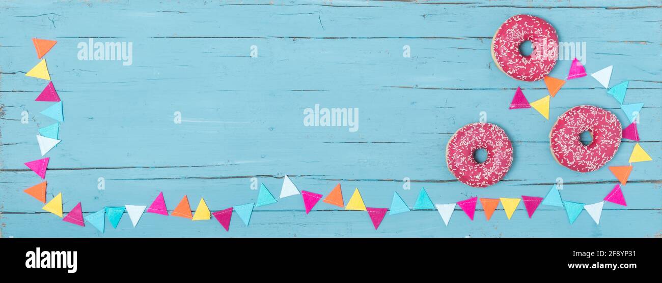 Three pink donuts and a party garland on a turquoise wooden background as banner Stock Photo