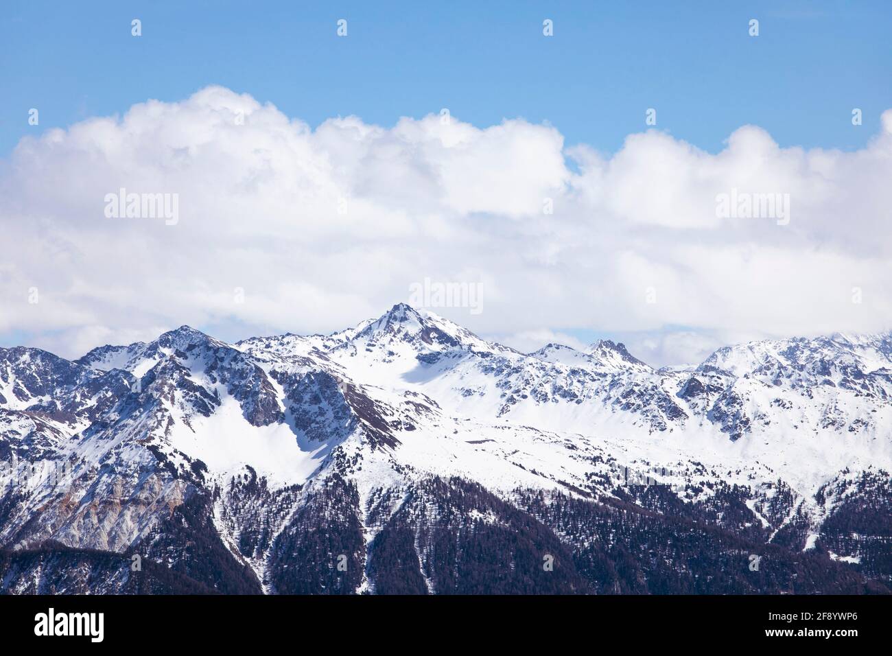 Winter landscape, snowcapped mountains with cloudscape, blue sky. Snowy mountain peaks in Swiss alps, Wallis. Stock Photo