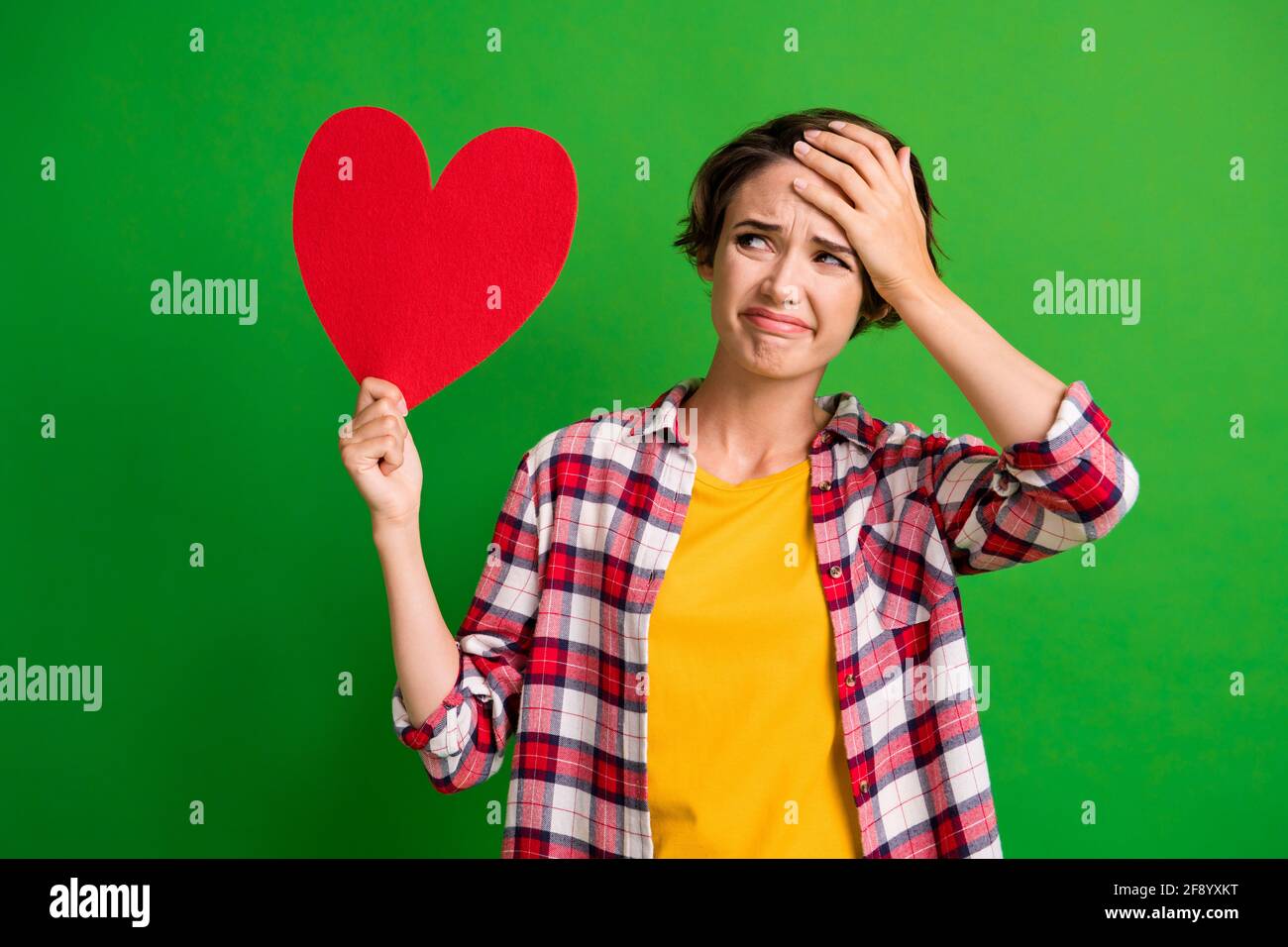 Photo of attractive person look empty space arm hold heart shape cry plaid style isolated on green color background Stock Photo