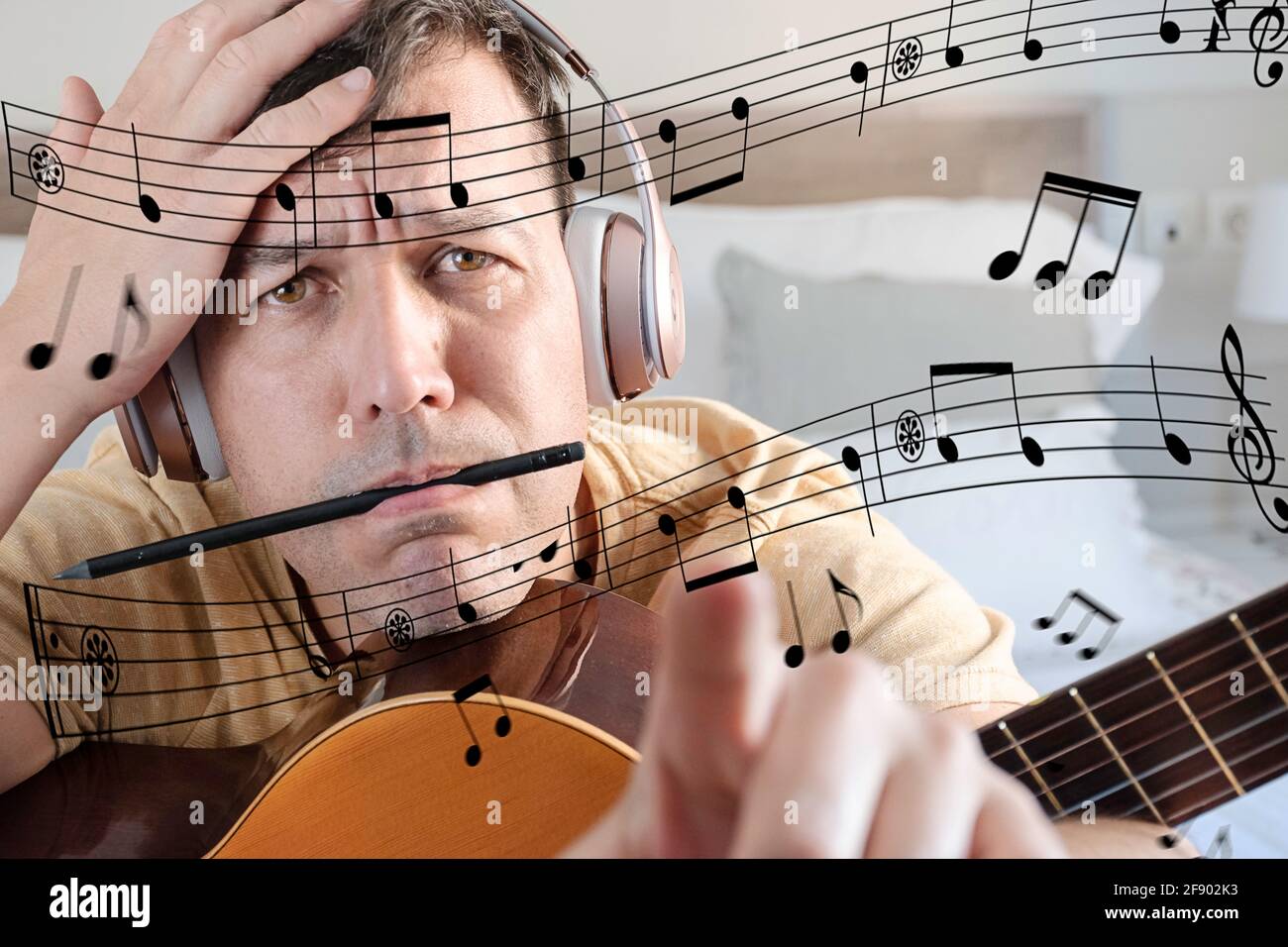 Man with a guitar looking at musical notes he does not understand Stock Photo