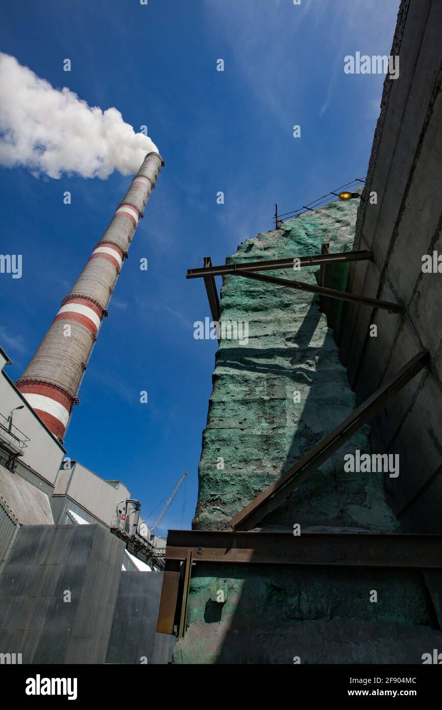 Ekibastuz,GRES-1 thermal power station.Grey raw coal bunkers and smoke stack with white smoke left.Boiler pipe with green thermal insulation right. Stock Photo
