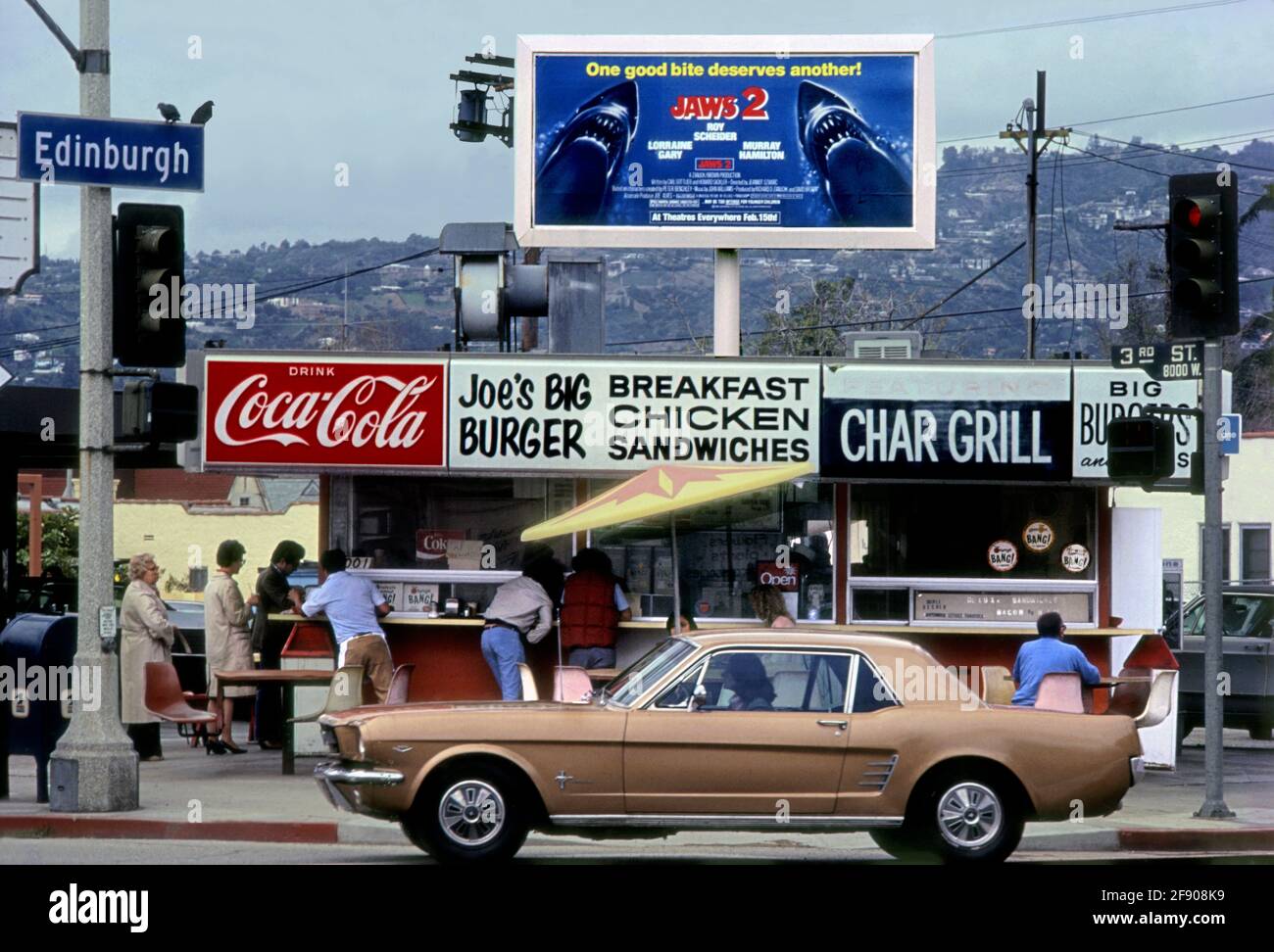A classic 1965 Ford Mustang passes in front of Joe's Big Burger at Edinburgh and 3rd Street near the Farmers Market in Los Angeles, CA Stock Photo
