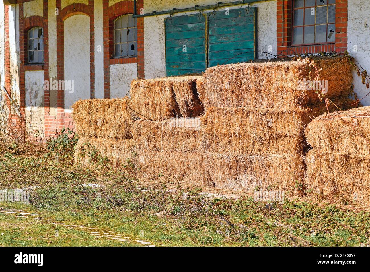 Rectangular hay bales in front of old abandoned farm building Stock Photo