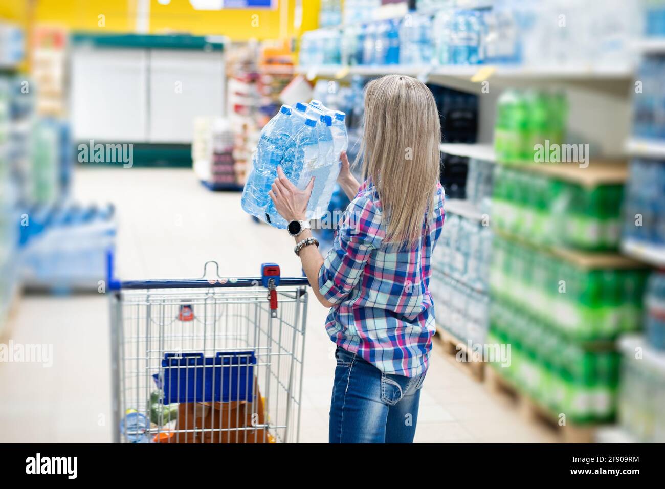 A woman buys water bottles at a grocery supermarket. She puts the
