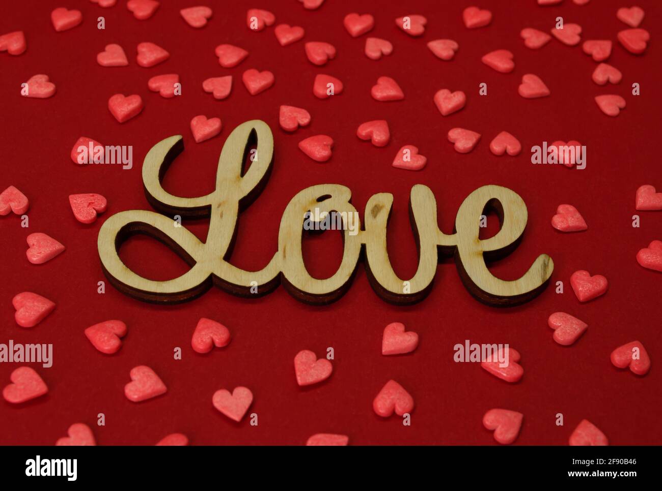 Wooden inscription Love hearts around on a red background Stock Photo