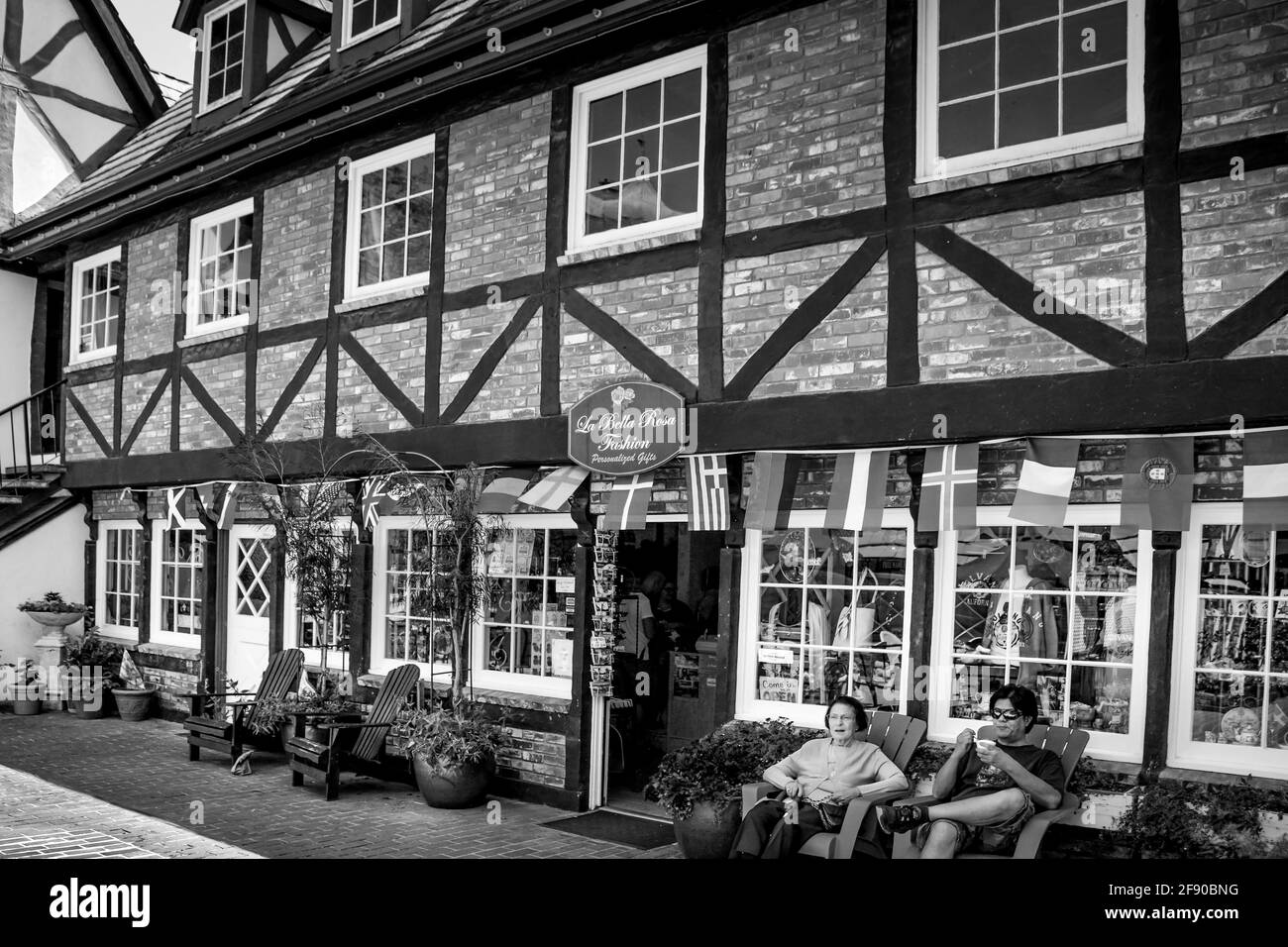 An inviting entrance to a shop in a Bavarian half timber style building with garden chairs for tourists in the faux Danish village, Solvang, CA, B&W Stock Photo