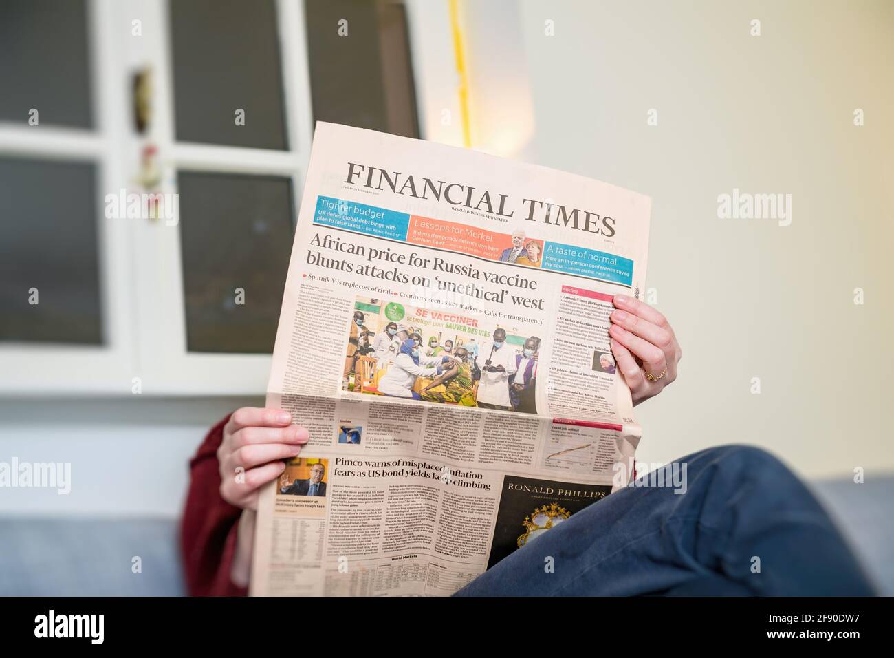 Woman reading in living room the latest Financial Times Business Stock Photo