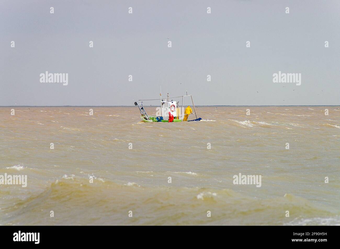 Small fishing boat, fishing in the Mediterranean off Fuengirola, Spain. Local fishermen net fishing inshore, close to the shore in heavy swell Stock Photo