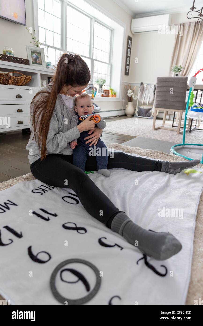 Loving mother sitting on floor holding her happy baby boy. Stock Photo