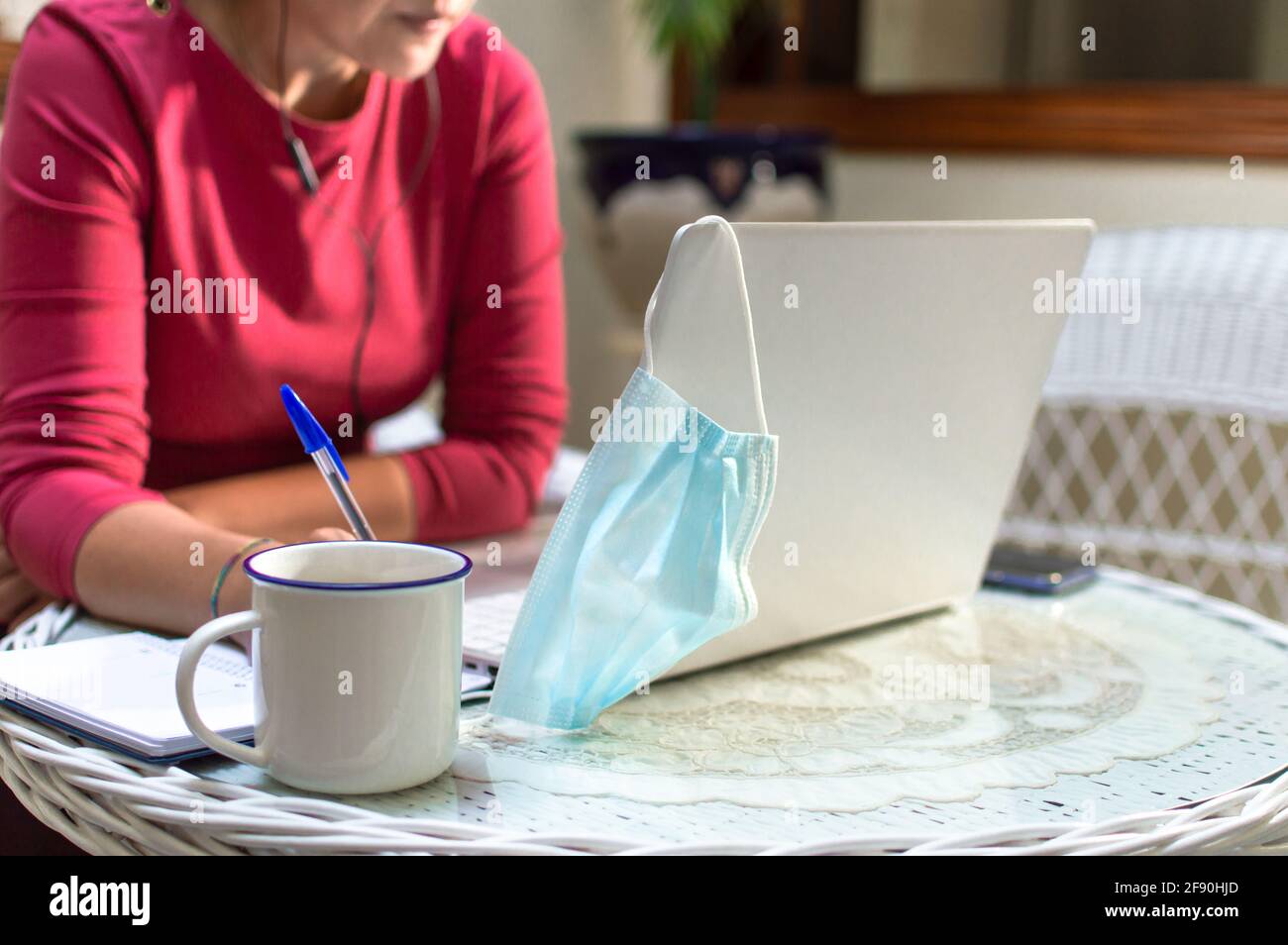 Unrecognized woman removes face mask to work from home. Working from home concept. Stock Photo