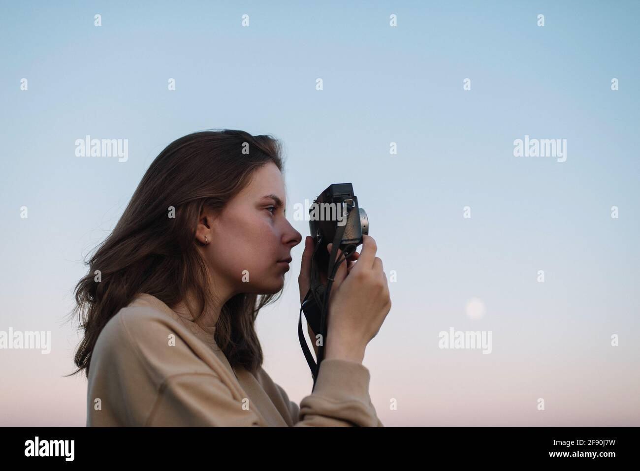 Woman taking pictures outdoor with a film camera during a sunset Stock Photo