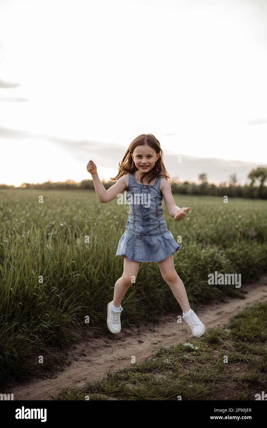 Happy 5 years old girl is jumping in a green field with long hair Stock ...