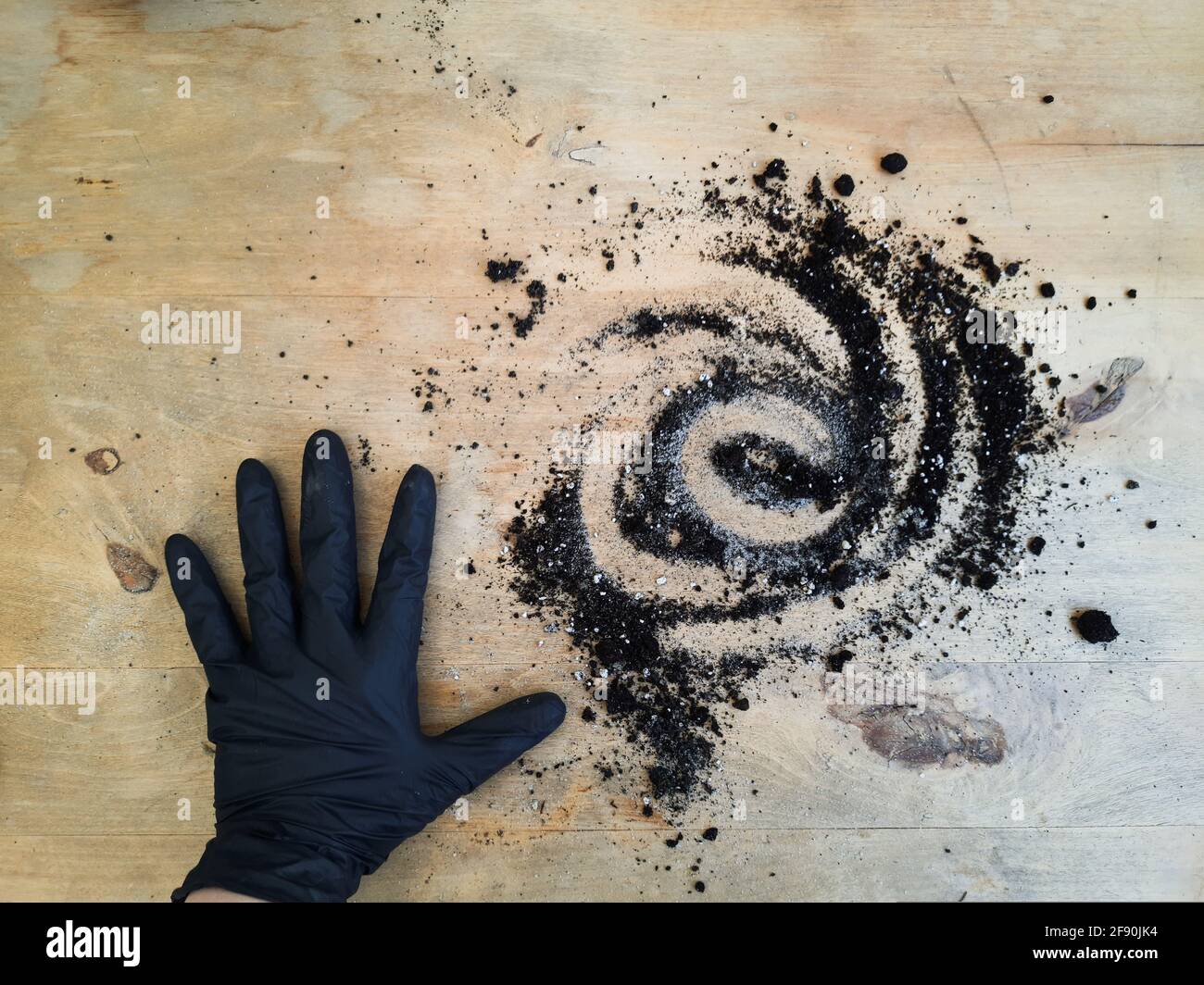 hand in black garden glove, helical soil on wooden table Stock Photo