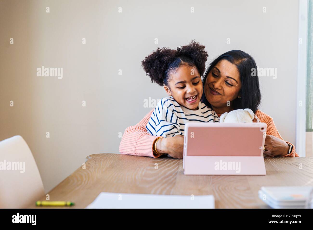 Smiling granddaughter and grandmother using digital tablet at home Stock Photo