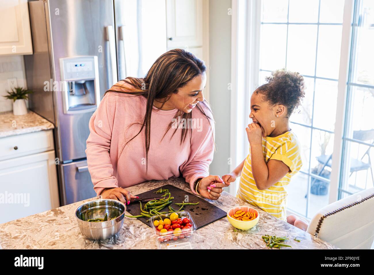 Cheerful mother and daughter preparing food at home Stock Photo