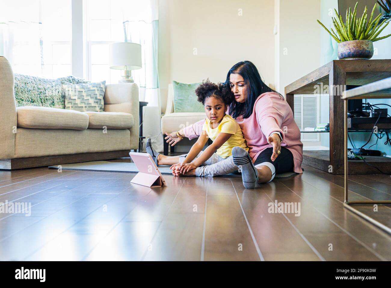 Girl practicing yoga with grandmother during online exercise class at home Stock Photo