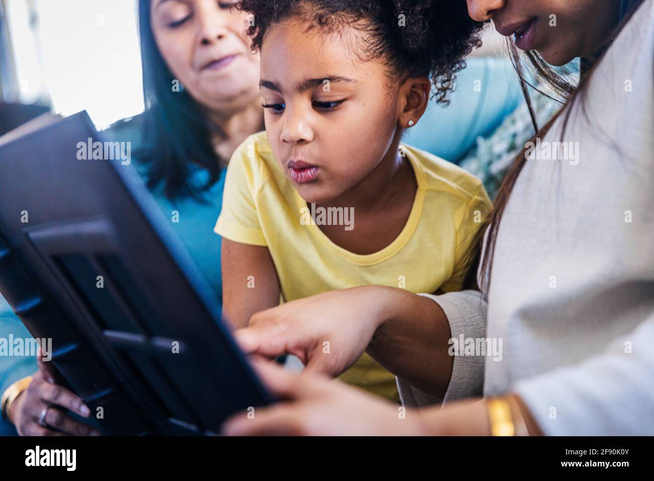 Cute girl looking at photo album while sitting with family at home Stock Photo