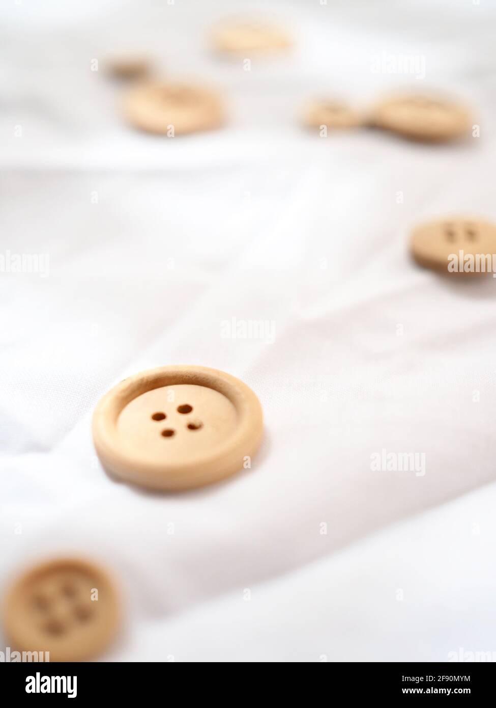 Up close image of a wooden button on a bright white textured background ...