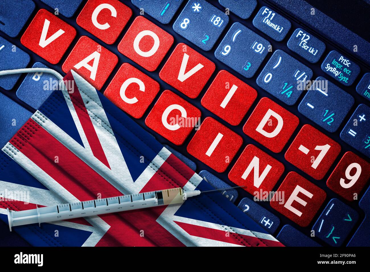 COVID-19 immunization in UK showing syringe and face mask with British flag and vaccine message on computer keyboard. Concept of Covid vaccination in Stock Photo