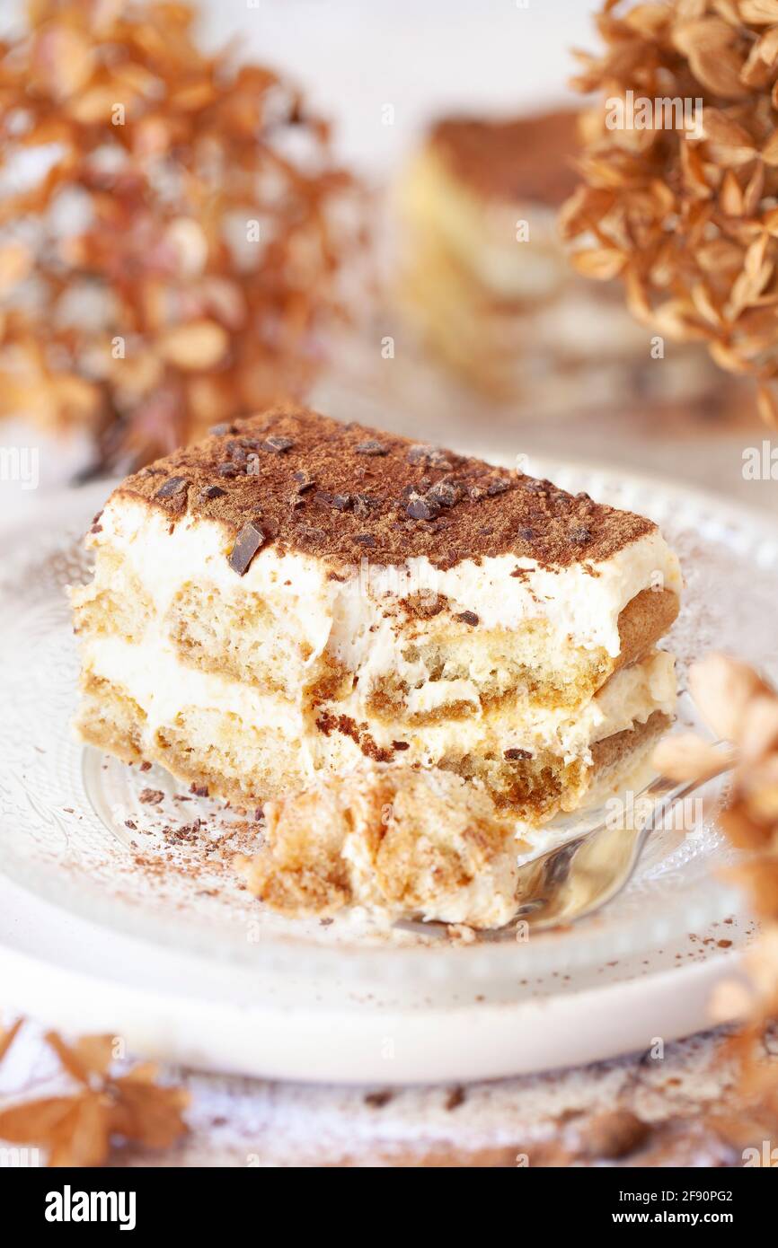 A slice of part eaten  tiramisu dessert on a glass plate Stock Photo