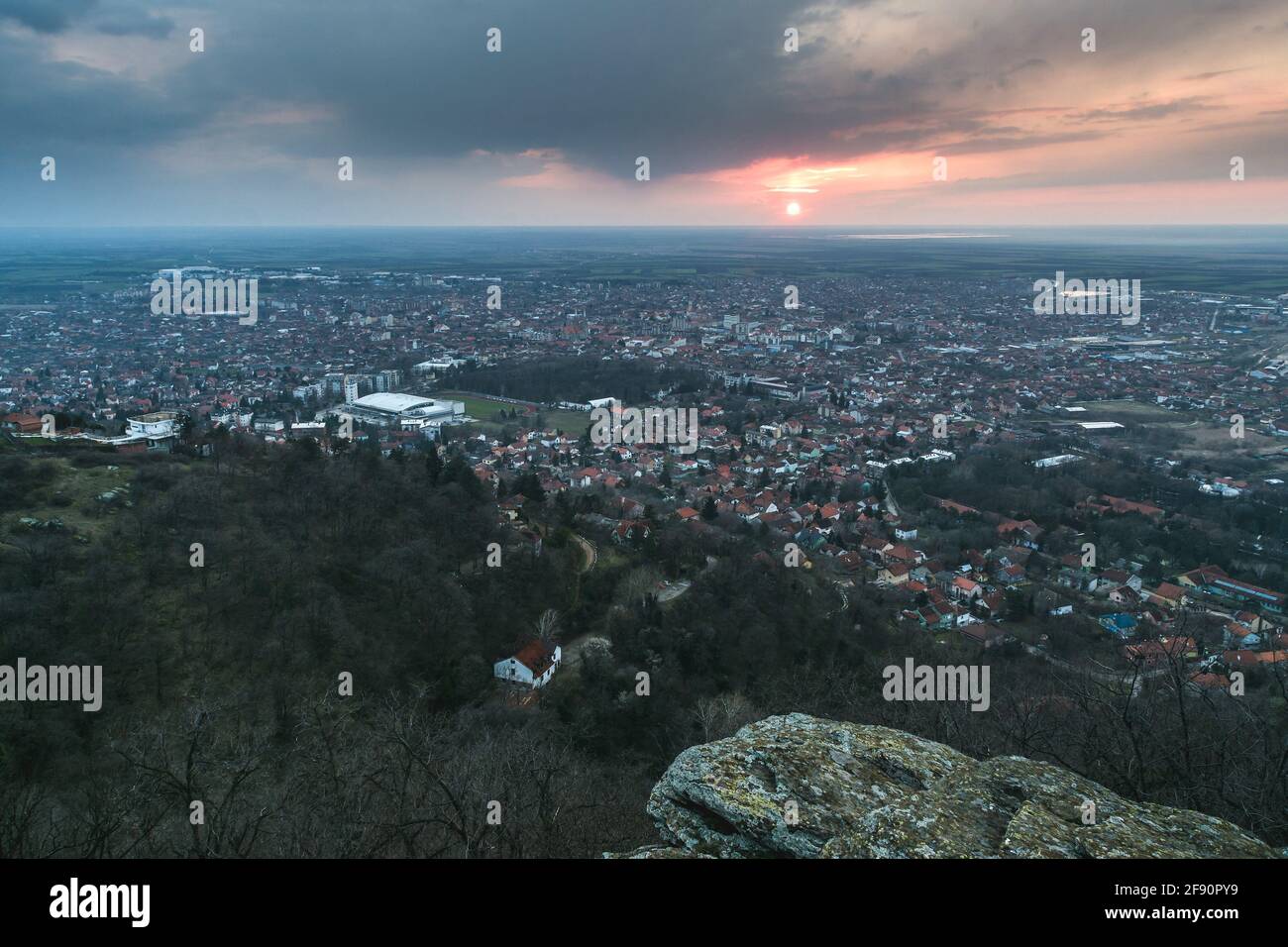 Hiker standing on the cliff above the Vrsac city in Serbia at sunset Stock Photo