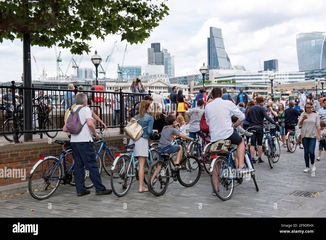 Family cyclists stationary amongst pedestrians on South Bank path seen from behind Stock Photo