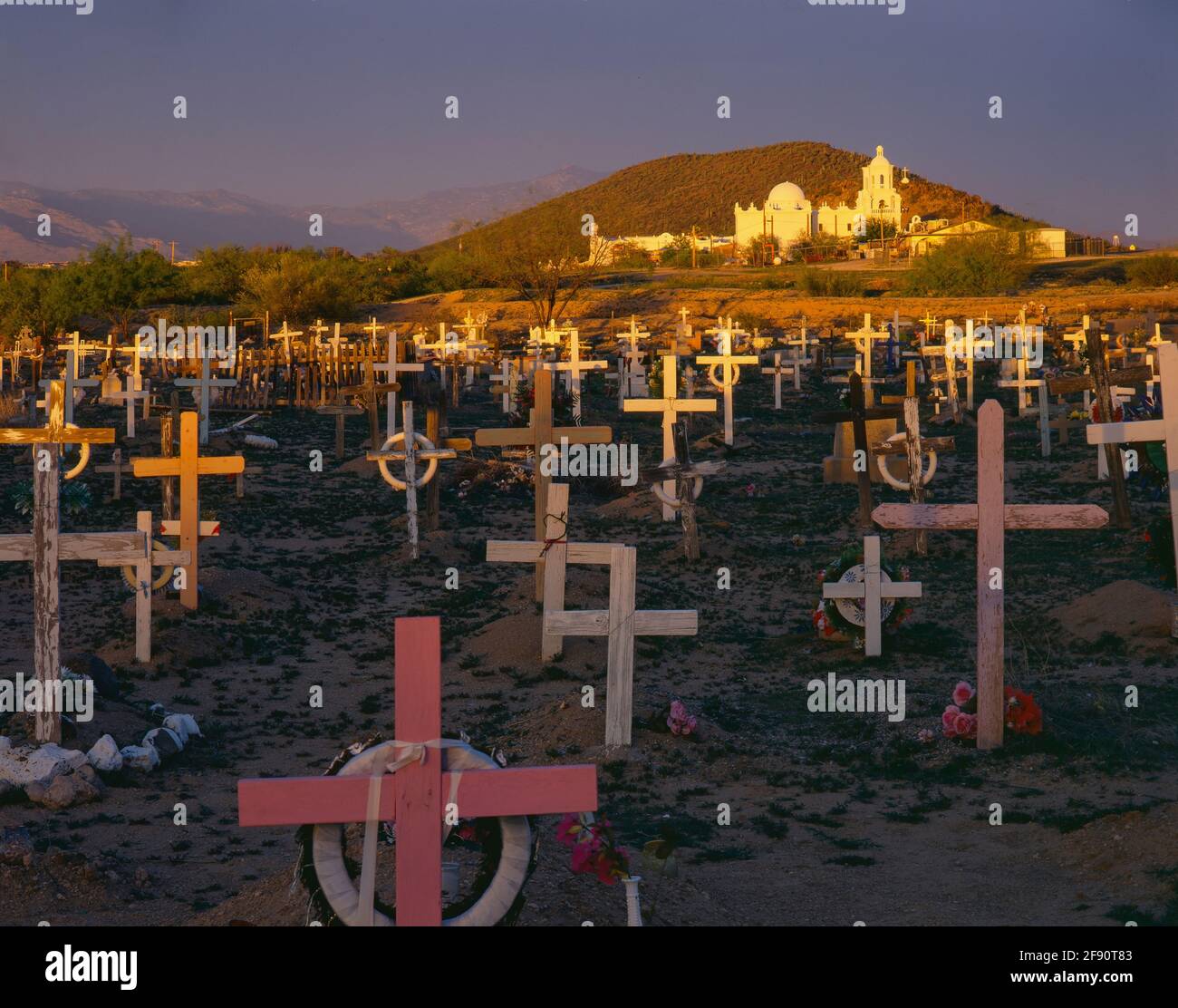 TOHONO O'ODHAM NATION,  AZ/MY SAN XAVIER MISSION AND RINCON MTNS ON  HORIZON BEYOND A CEMETERY THICK WITH  DECORATED WOODEN CROSSES Stock Photo