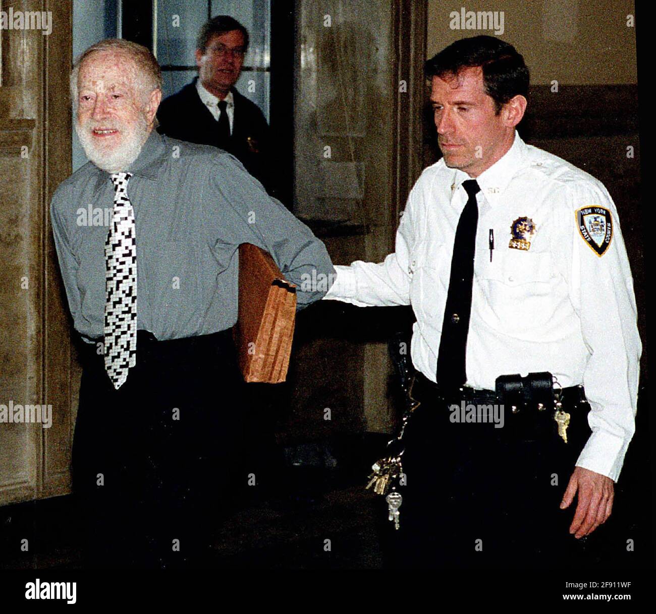 Queens NY 2000 Handcuffed and escorted by officers, 80 year old Abe Hirschfeld, is brought to NY Supreme Court where he is being sued by a group of co-op owners who claim he misappropriated two million dollars.(Photo©Neil Schneider) Stock Photo
