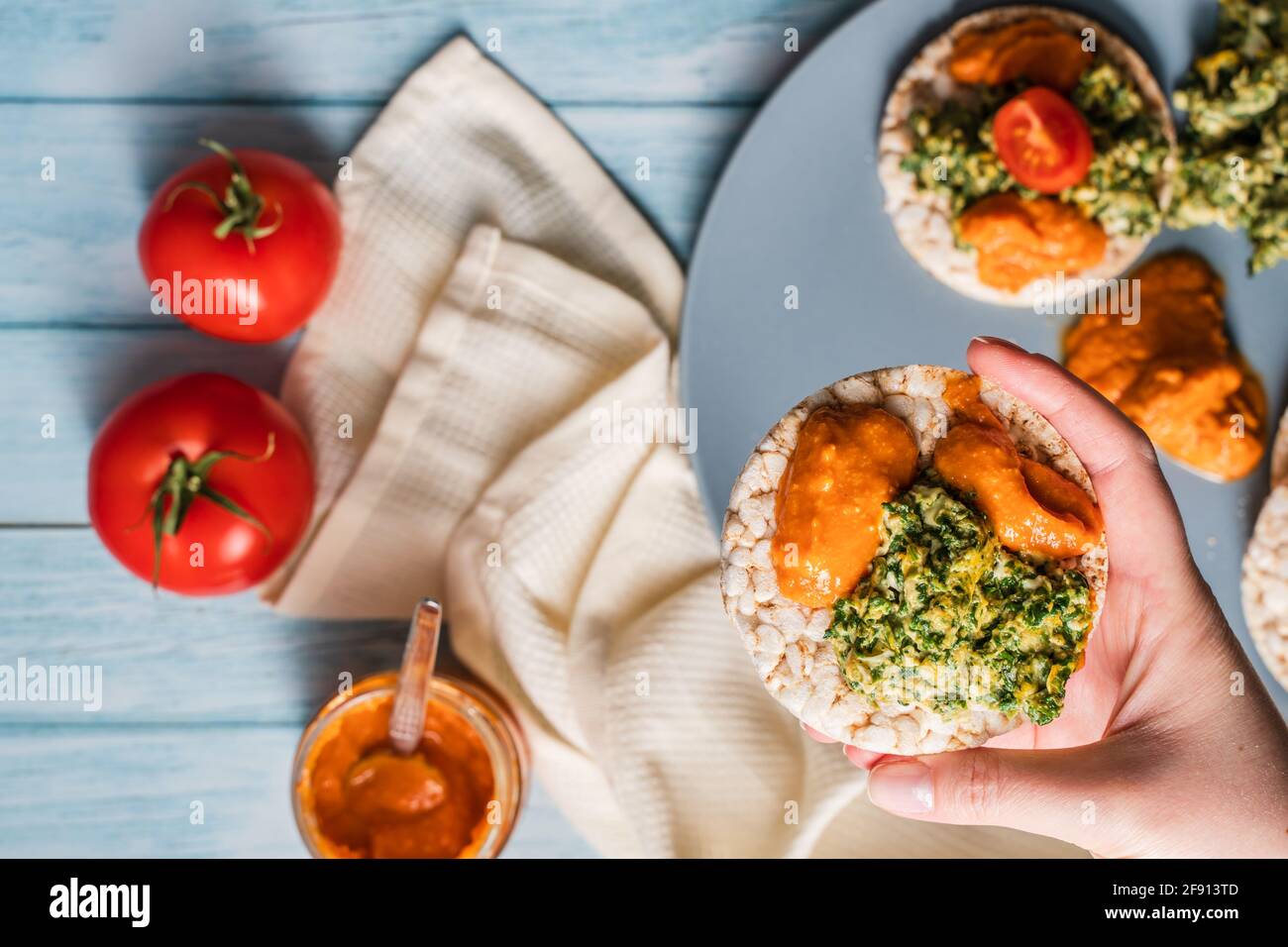 Crispy puffed rice cakes on table with hummus spread spinach with eggs